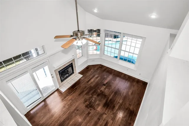 an empty room with wooden floor fireplace and windows