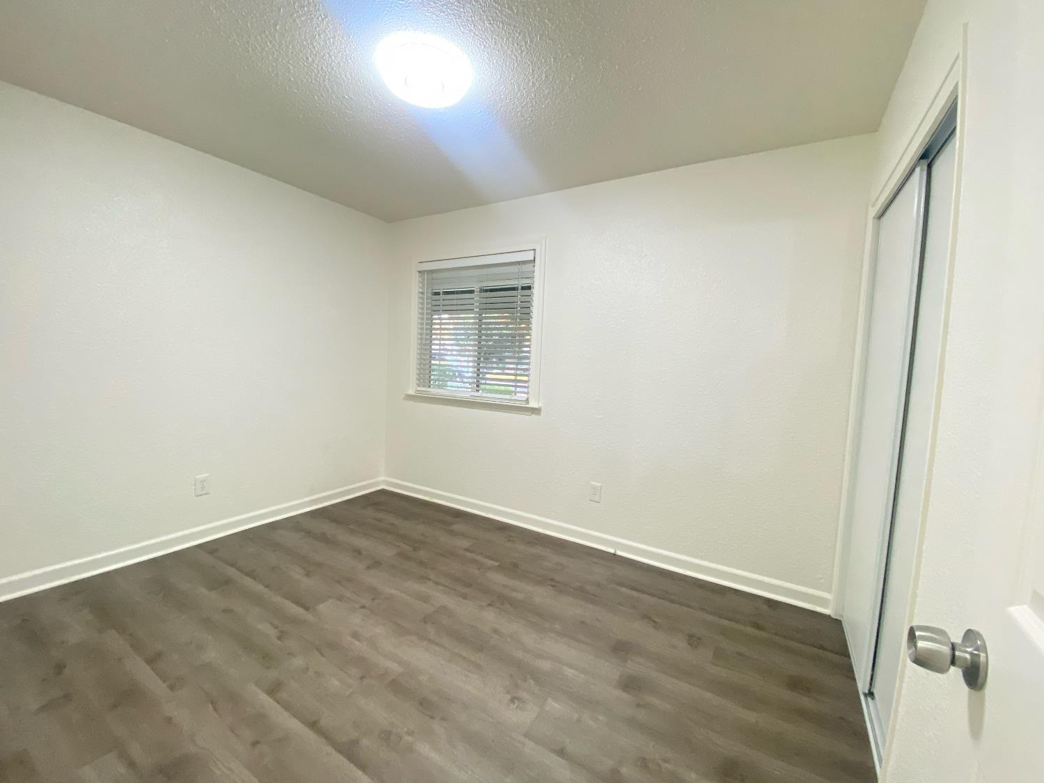 2301 McRitchie Way Modesto, CA 95355 - Photo 13 of 22 an empty room with wooden floor and windows