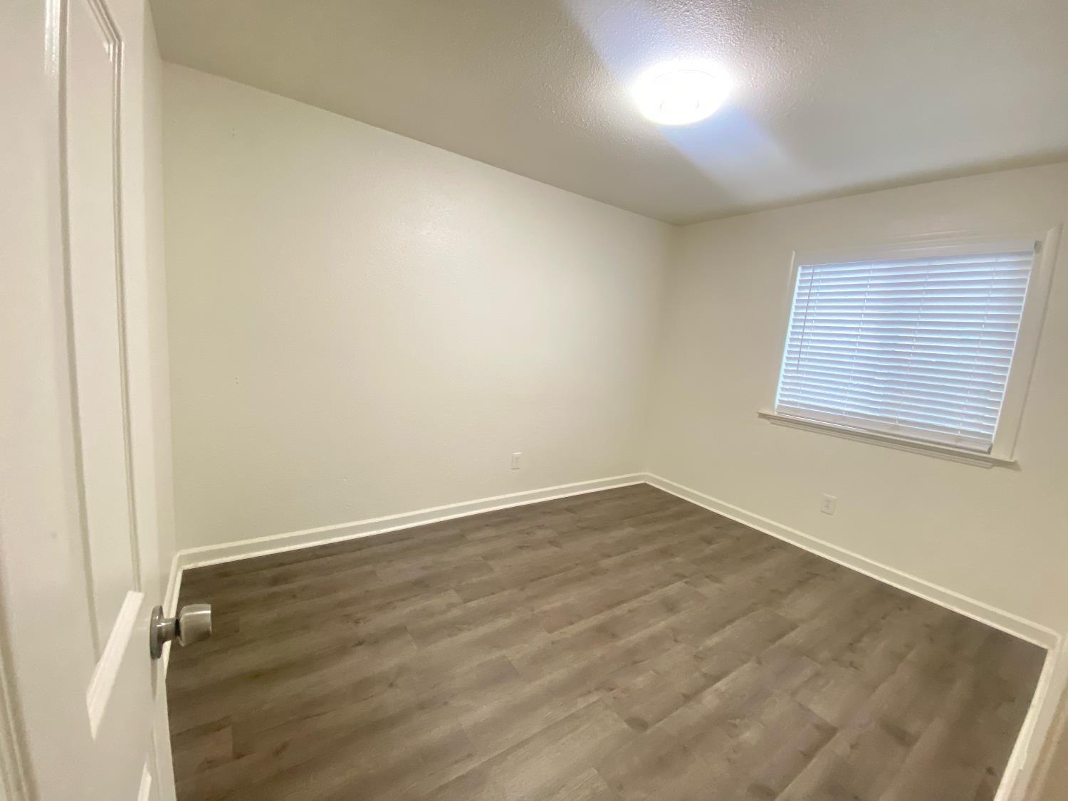 2301 McRitchie Way Modesto, CA 95355 - Photo 15 of 22 an empty room with wooden floor and windows