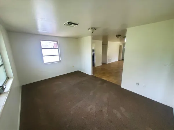 an empty room with windows and refrigerator