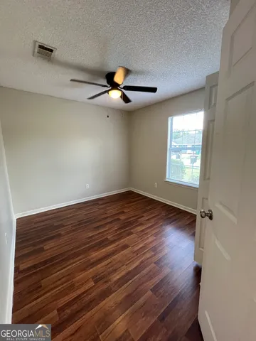an empty room with wooden floor closet and windows