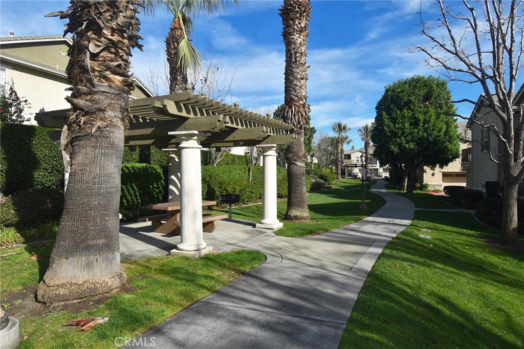 7353 Ellena West, Unit 70 Rancho Cucamonga, CA 91730 - Photo 24 of 40 a view of a house with a yard and table and chairs under a large tree