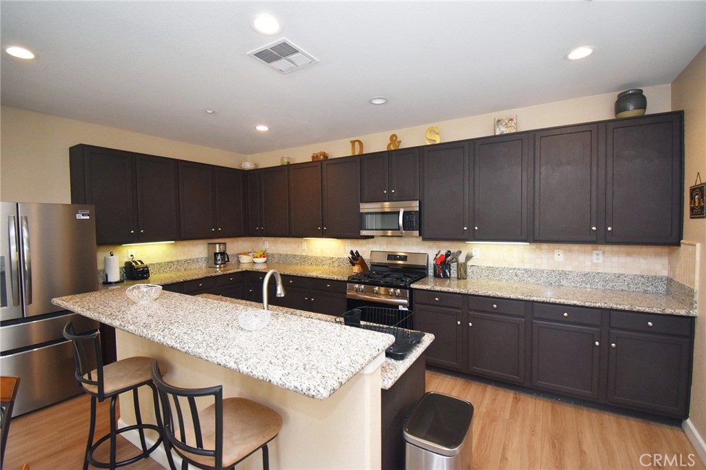 7353 Ellena West, Unit 70 Rancho Cucamonga, CA 91730 - Photo 6 of 40 a kitchen with granite countertop a table chairs sink and cabinets