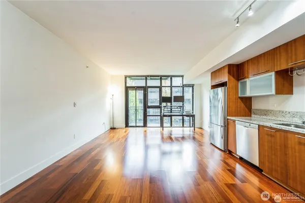 a view of an empty room with wooden floor and a window