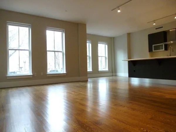 a view of an empty room with wooden floor and a window