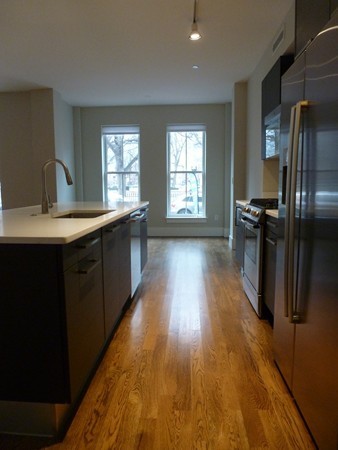 10 St George Street, Unit 103 Boston, MA 02118 - Photo 6 of 8 a kitchen with stainless steel appliances granite countertop a refrigerator a sink dishwasher a stove and white countertops with wooden floor