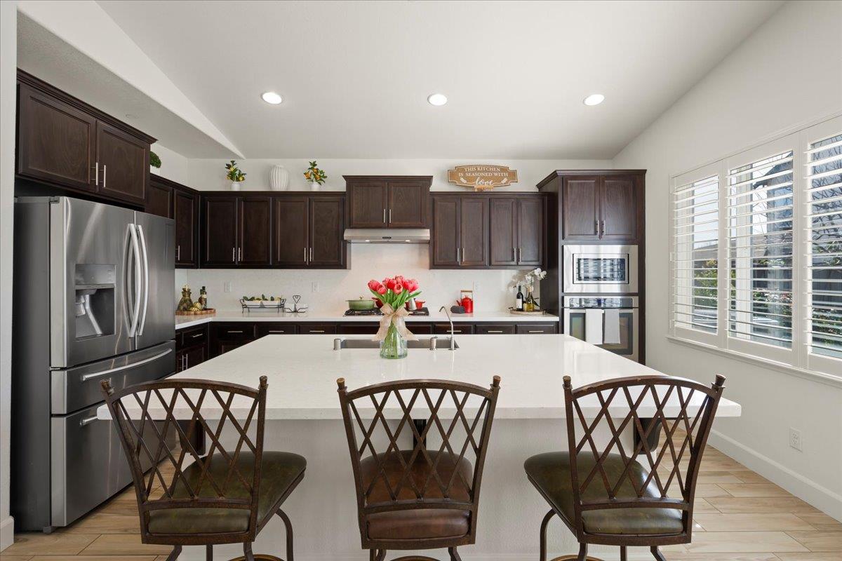 1188 Viognier Way Gilroy, CA 95020 - Photo 23 of 71 a kitchen with stainless steel appliances granite countertop a dining table chairs refrigerator and microwave