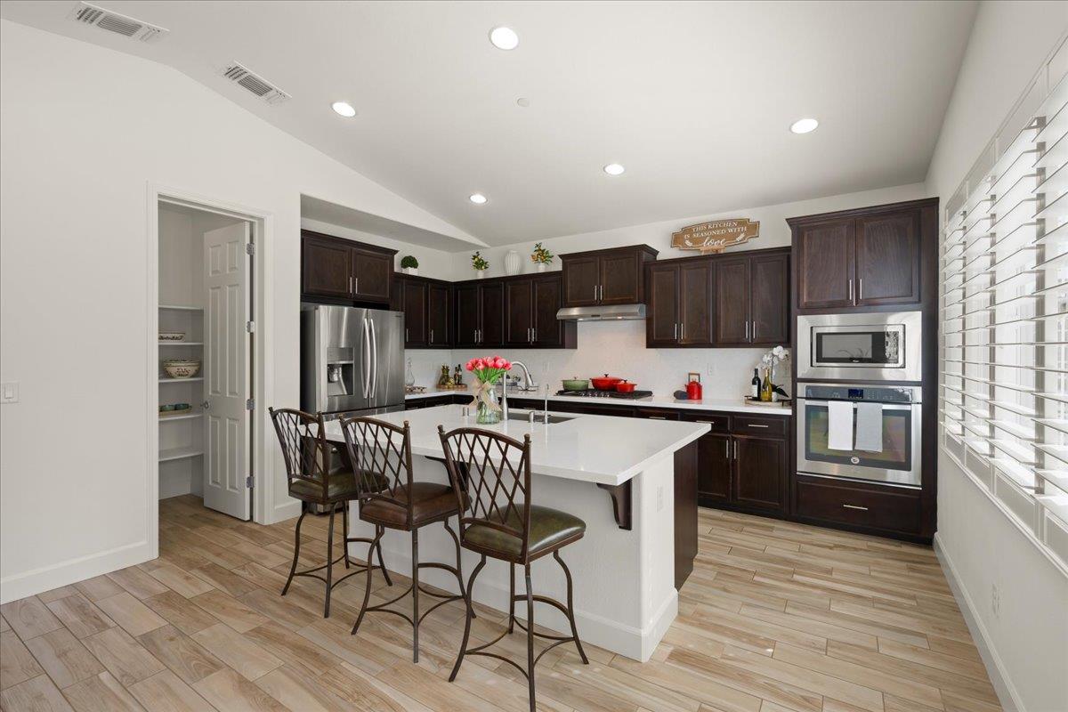 1188 Viognier Way Gilroy, CA 95020 - Photo 24 of 71 a kitchen with stainless steel appliances a microwave a stove a refrigerator cabinets a dining table and chairs
