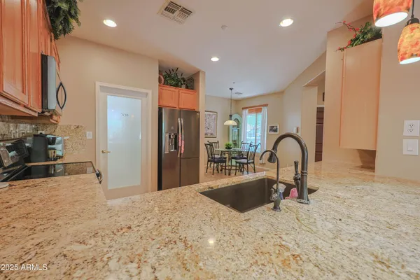 a kitchen with stainless steel appliances kitchen island a sink a refrigerator and a granite counter tops