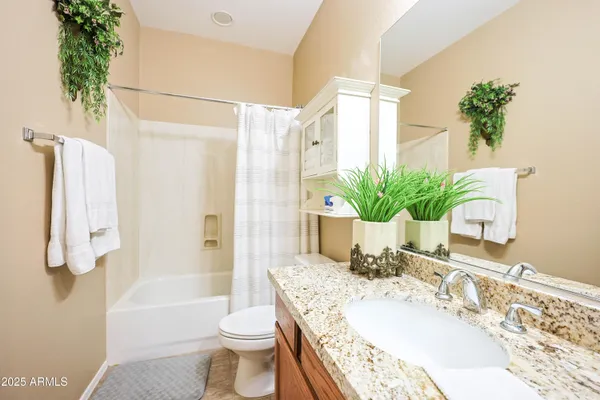 a bathroom with a granite countertop sink a toilet and tub