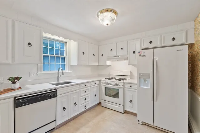 a kitchen with cabinets appliances a sink and a window