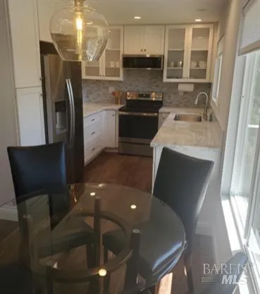 a kitchen with stainless steel appliances granite countertop a refrigerator a stove a sink a dining table and chairs