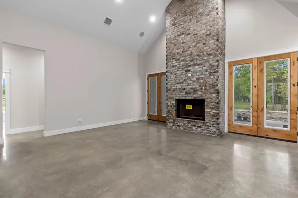a view of an empty room with wooden floor fireplace and a window