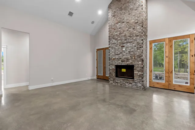 a view of an empty room with wooden floor fireplace and a window