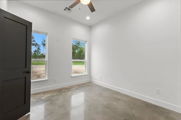 an empty room with windows and ceiling fan