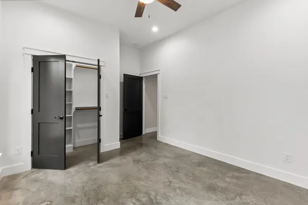 an empty room with closet and a chandelier fan