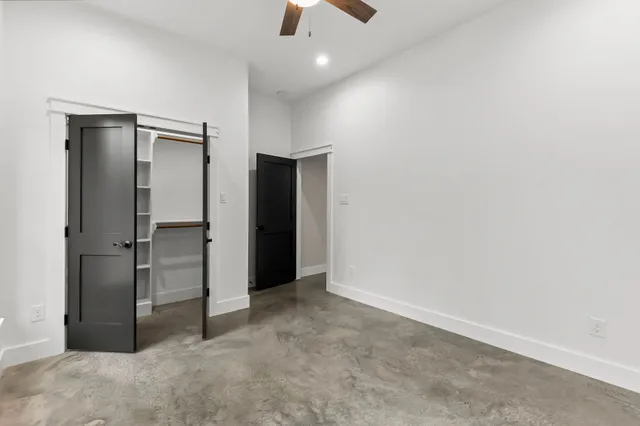 an empty room with closet and a chandelier fan