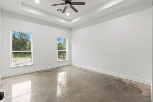 en empty room with windows and ceiling fan