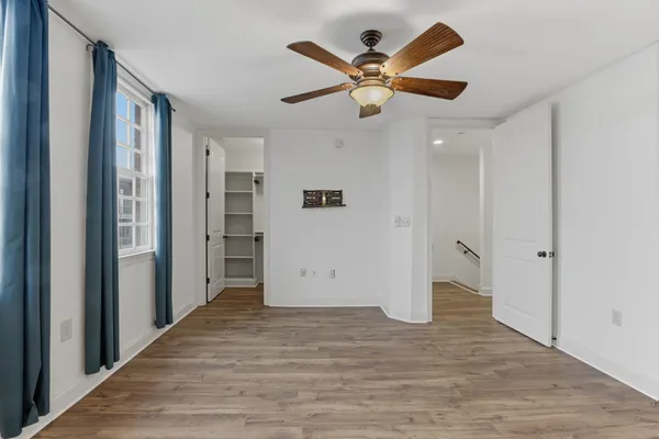a view of an empty room with wooden floor fireplace and a window