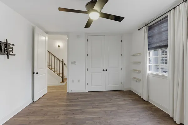 a view of a livingroom with a fireplace a ceiling fan and wooden floor