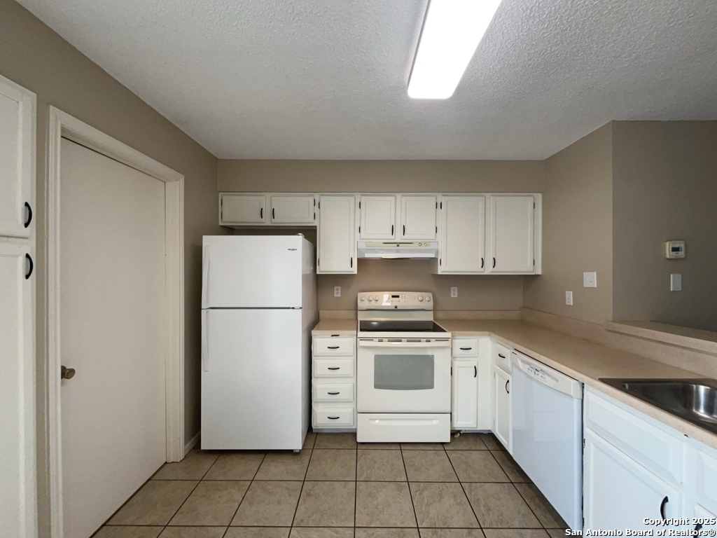 309 West Highland Drive Boerne, TX 78006 - Photo 11 of 32 a kitchen with a stove a refrigerator and white cabinets