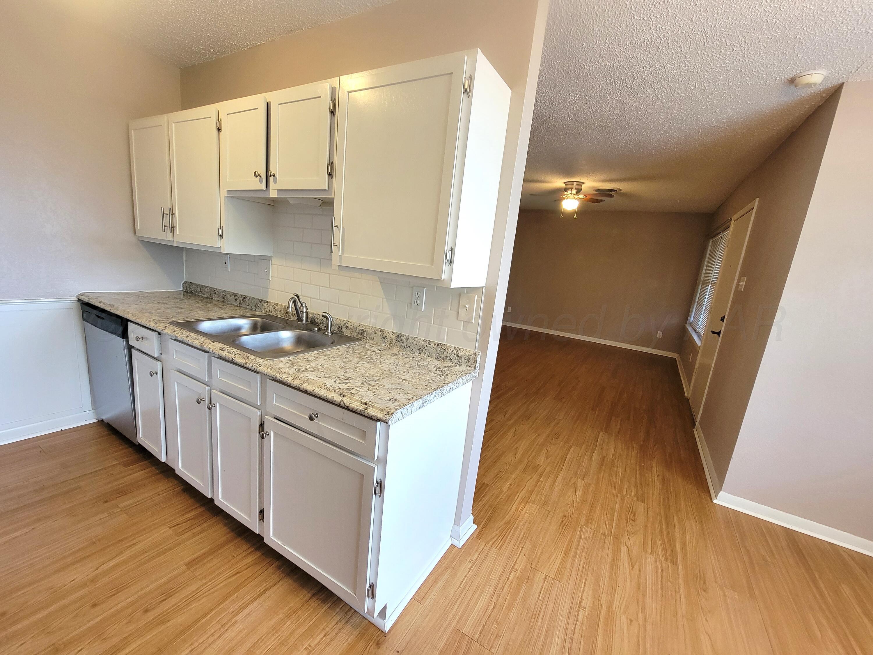 1312 Coffee Street Pampa, TX 79065 - Photo 16 of 31 a kitchen with granite countertop a sink stove and cabinets