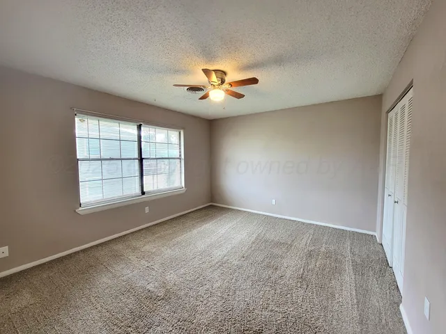 an empty room with windows and ceiling fan
