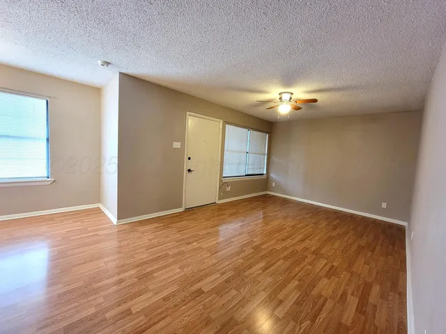 a view of an empty room with window and wooden floor