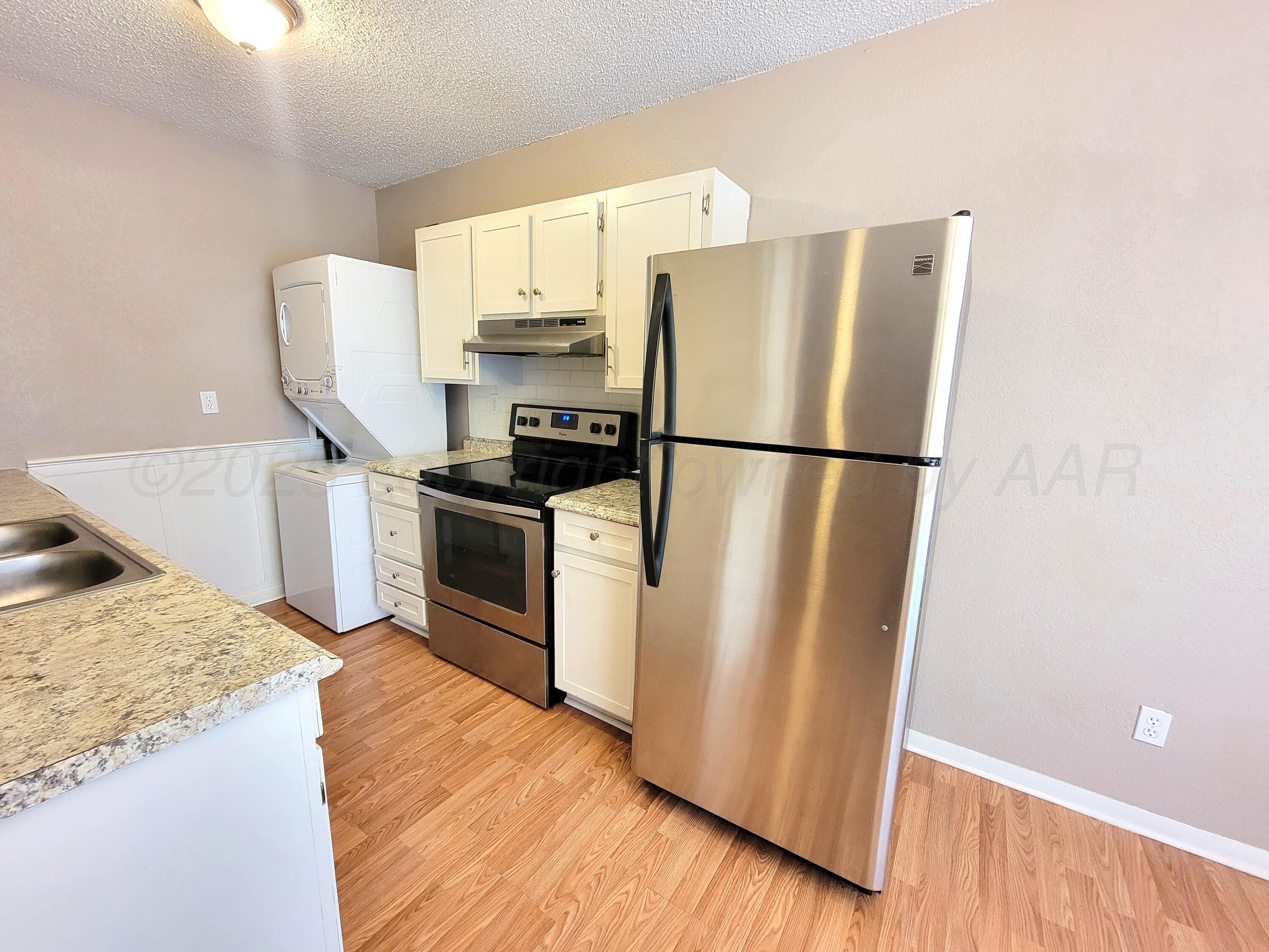 1312 Coffee Street Pampa, TX 79065 - Photo 26 of 31 a kitchen with granite countertop a refrigerator a stove a sink a washer and dryer