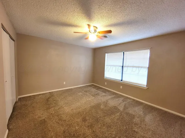 an empty room with windows and ceiling fan