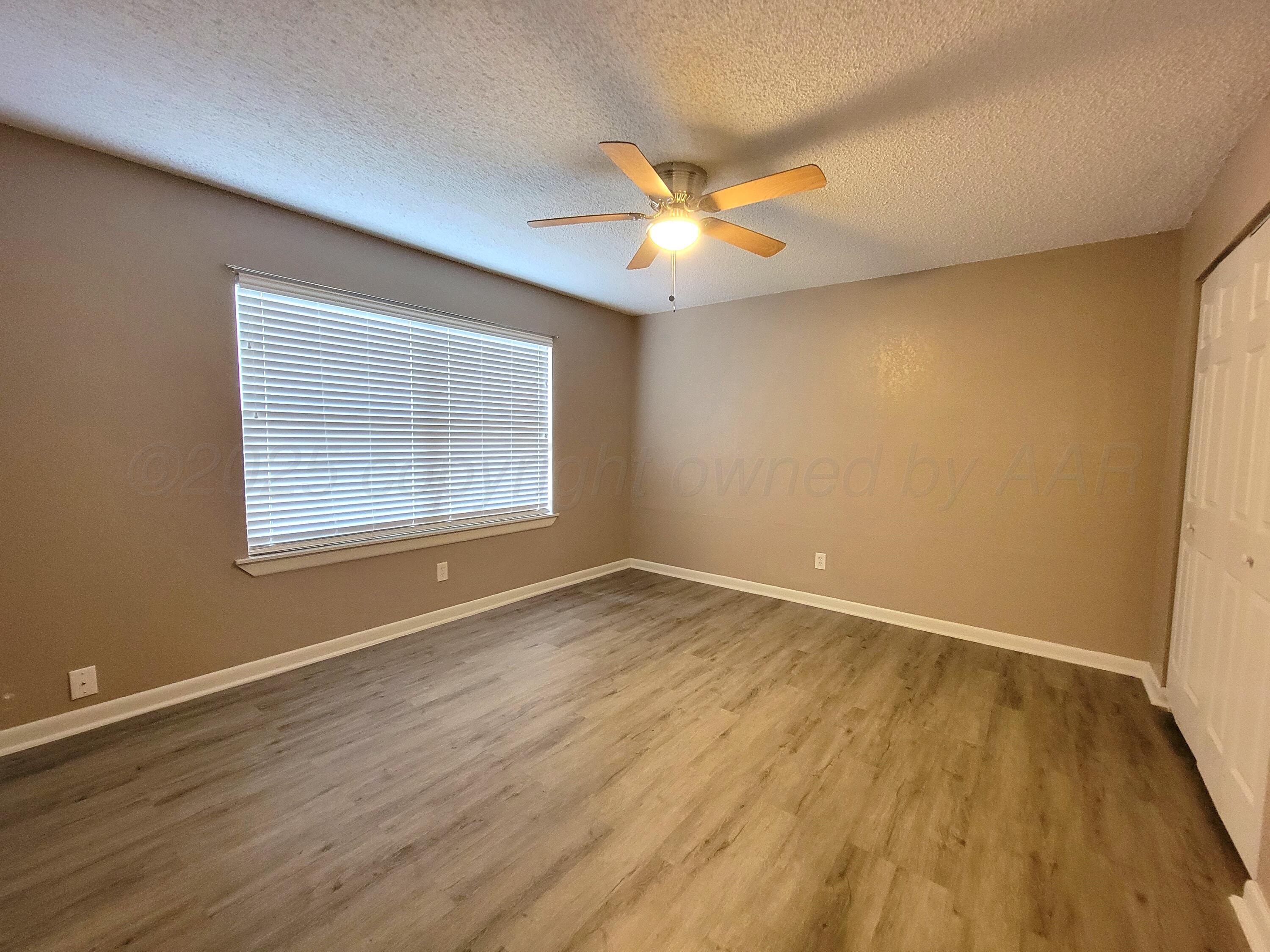 1312 Coffee Street Pampa, TX 79065 - Photo 7 of 31 an empty room with wooden floor fan and windows