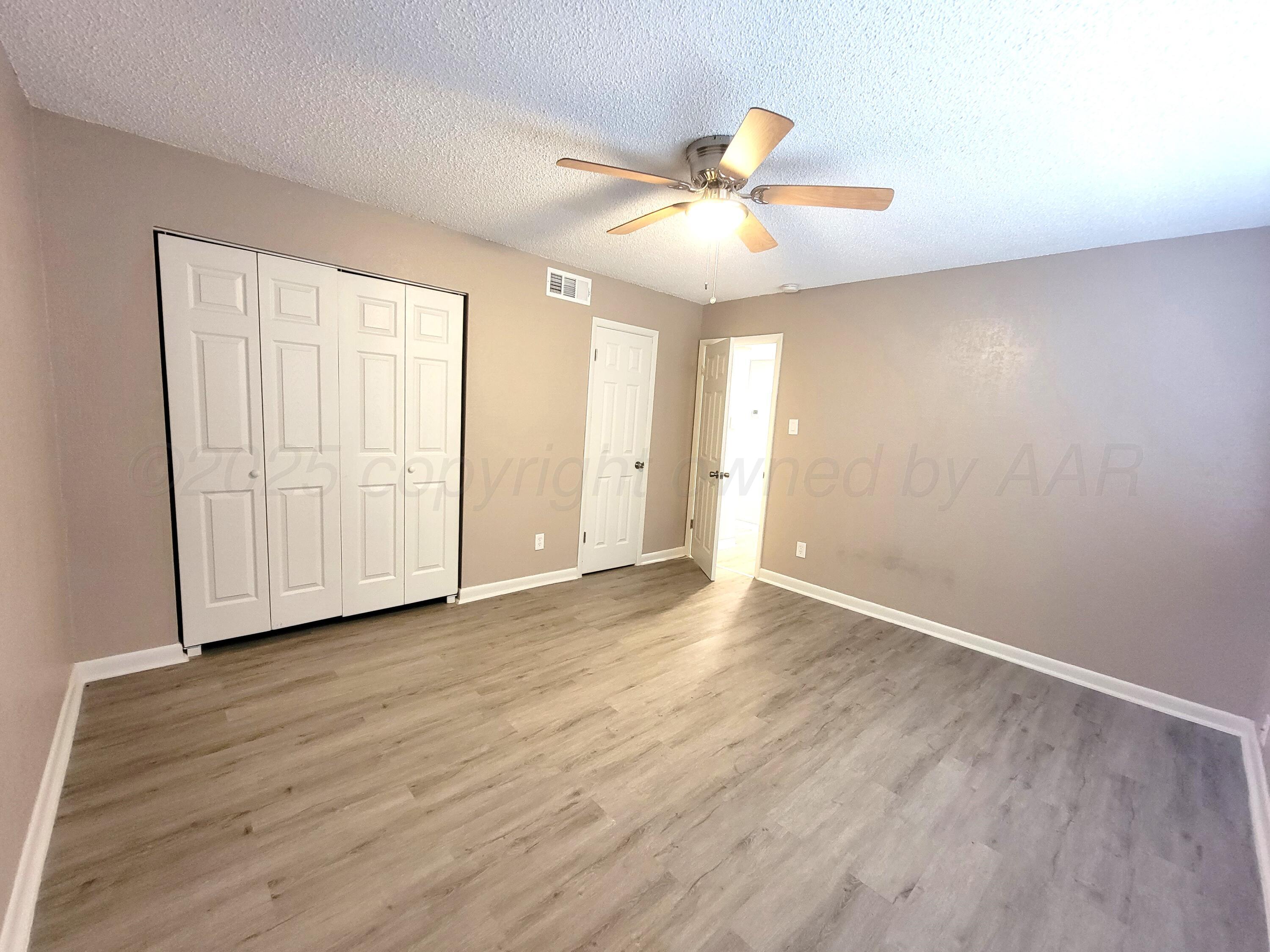 1312 Coffee Street Pampa, TX 79065 - Photo 8 of 31 an empty room with wooden floor fan and windows