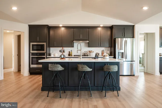 a kitchen with stainless steel appliances granite countertop a stove top oven a sink dishwasher a dining table and chairs with wooden floor