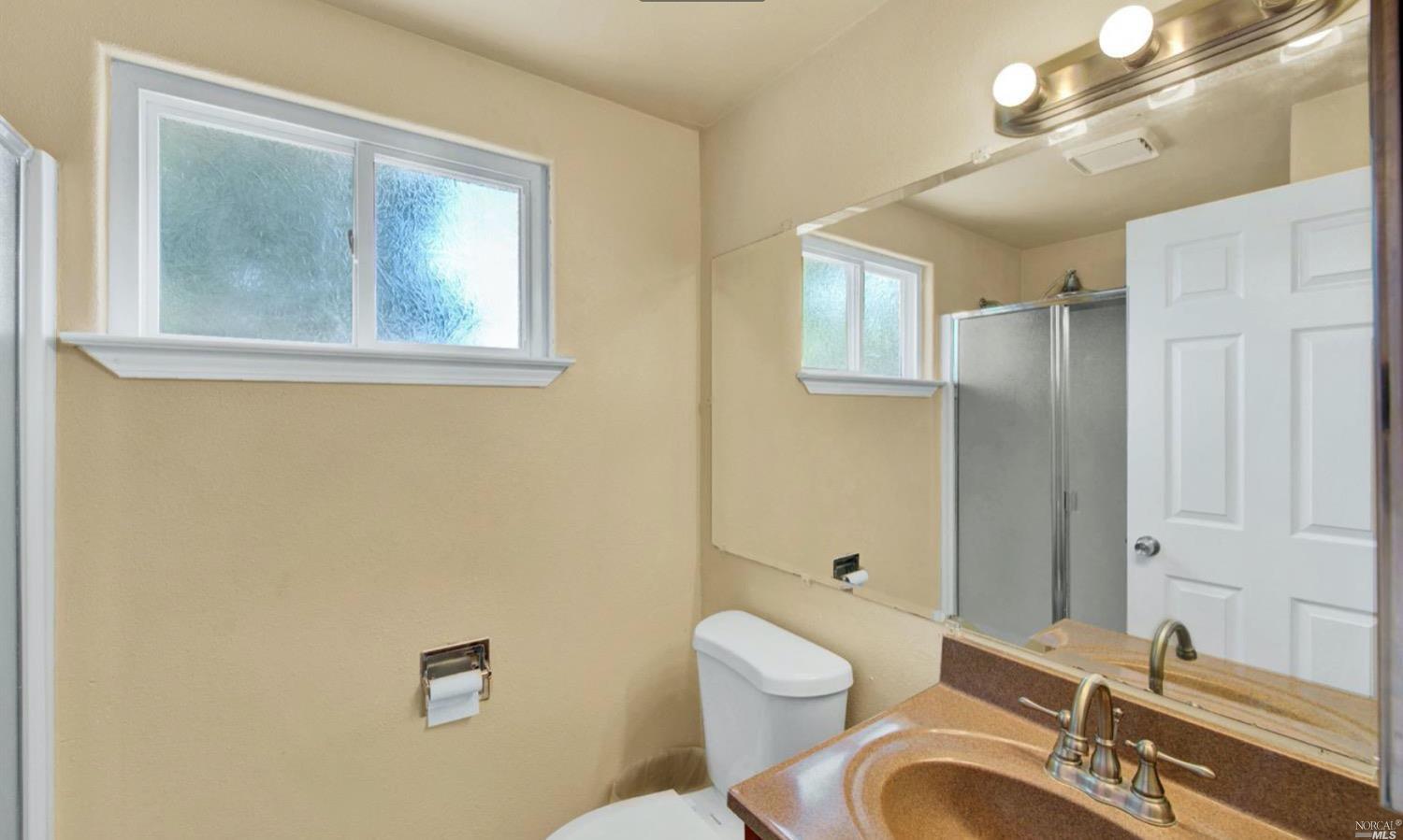 100 Arrowhead Court Vacaville, CA 95687 - Photo 23 of 40 a bathroom with a granite countertop toilet a sink and mirror