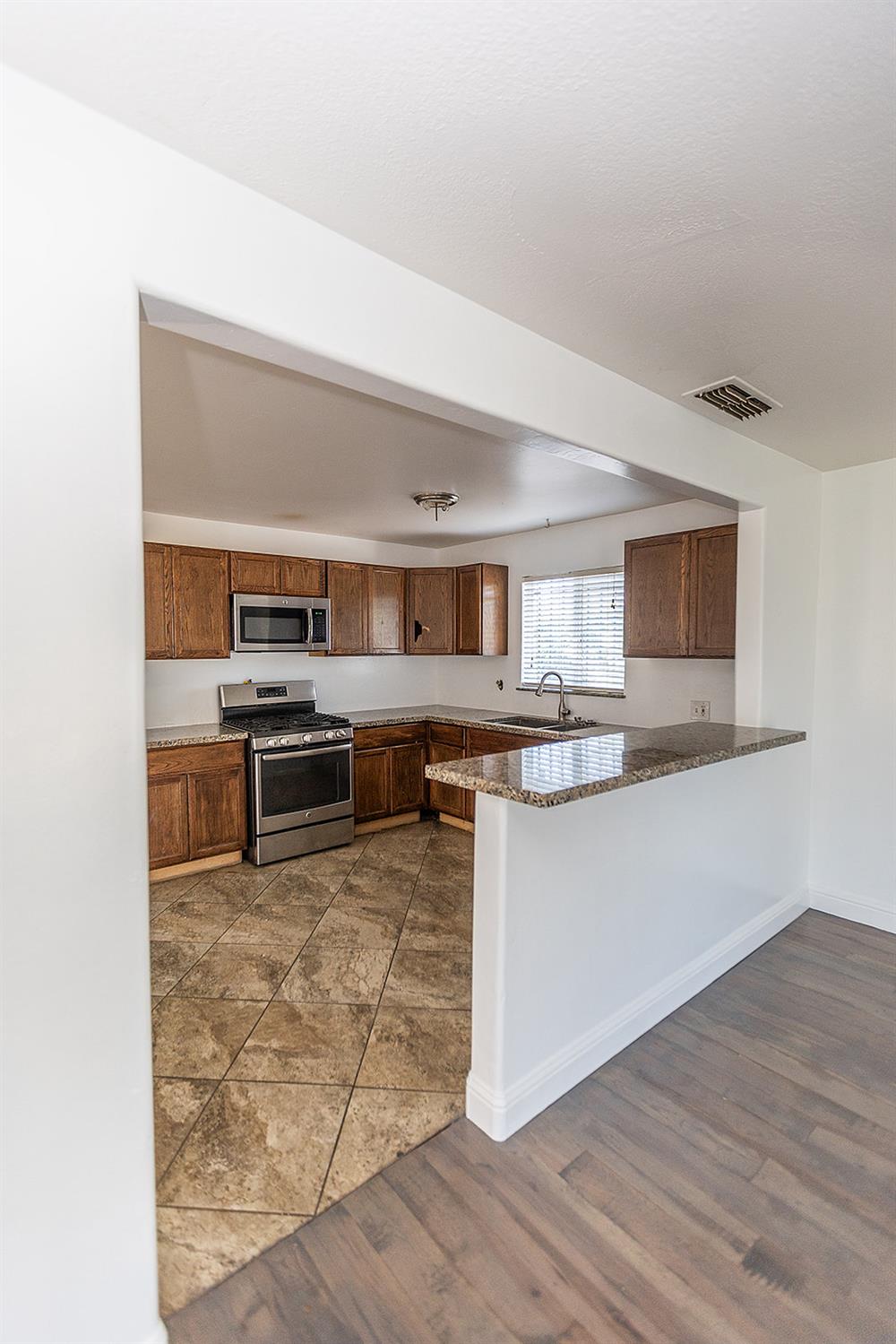 2105 Norman Way Modesto, CA 95350 - Photo 13 of 34 a kitchen with stainless steel appliances kitchen island granite countertop a stove a sink and a microwave