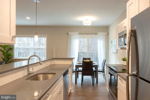a kitchen with granite countertop a sink stainless steel appliances and furniture