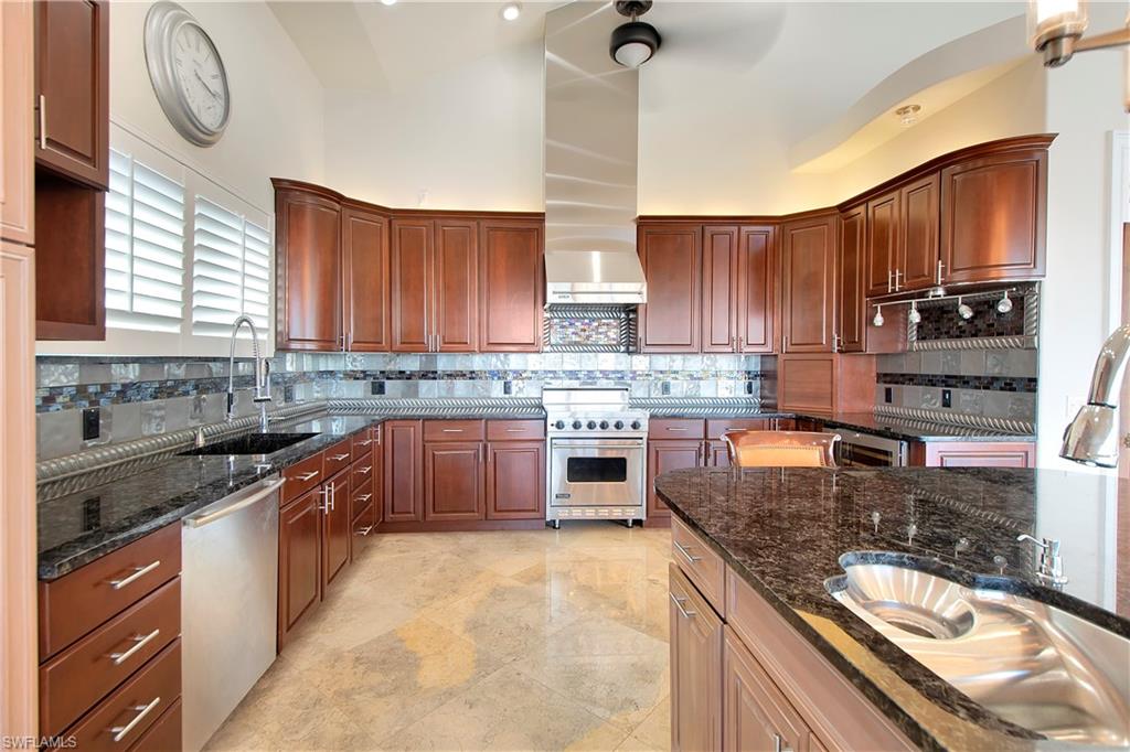 28 West Pelican Street Naples, FL 34113 - Photo 9 of 50 a kitchen with stainless steel appliances granite countertop a sink a stove top oven a counter space and cabinets