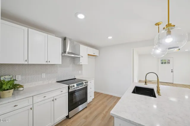 a kitchen with stainless steel appliances granite countertop a sink a stove and a wooden floors