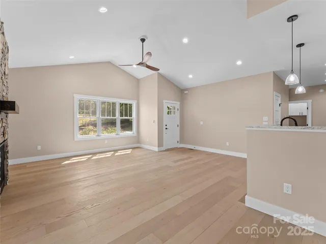 a view of an empty room with a window and kitchen view