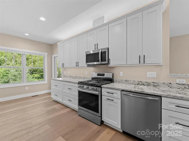 a kitchen with stainless steel appliances granite countertop a stove a sink and white cabinets