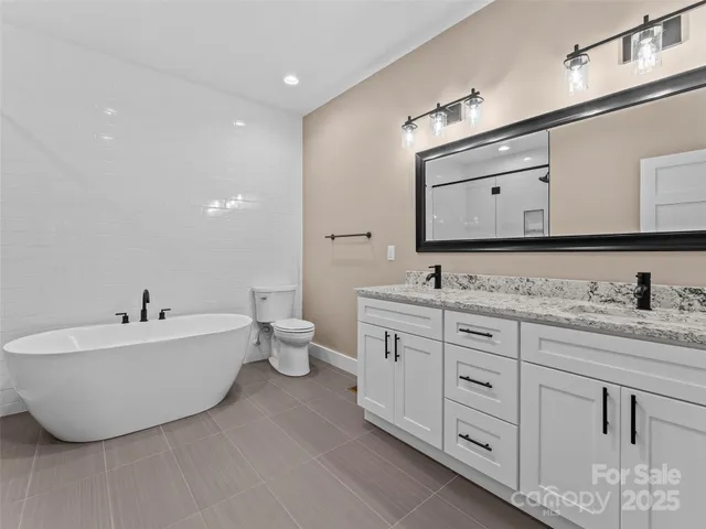 a spacious bathroom with a double vanity sink mirror and bathtub