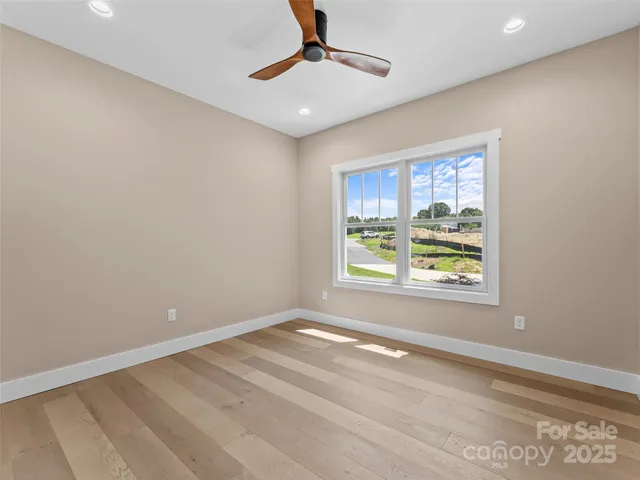 an empty room with windows and ceiling fan