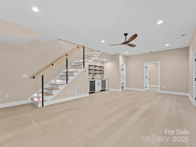 a view of an empty room with stairs and a ceiling fan