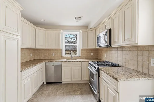 a kitchen with stainless steel appliances granite countertop a stove sink and cabinets