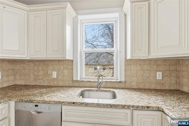 a kitchen with granite countertop a sink window and cabinets