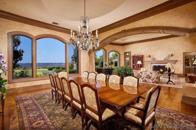 a view of a dining room with furniture a chandelier and large windows