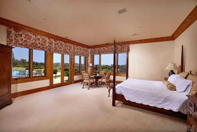 a bedroom with a bed and large windows