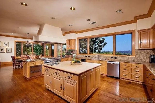 a kitchen with a stove a sink a refrigerator and chairs