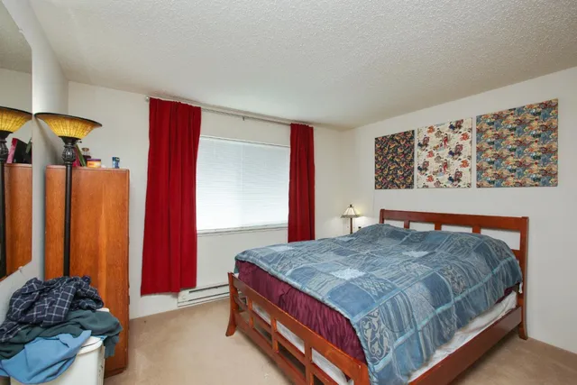 a bedroom with a bed and a lamp on dresser