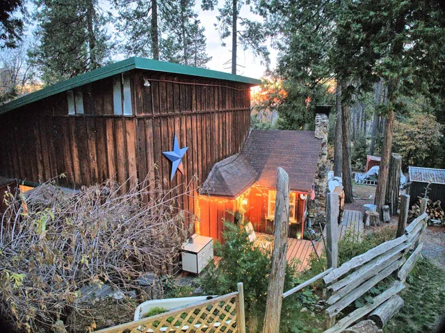 a view of a wooden house with a small yard and a large tree